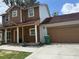 Charming two-story home with a covered front porch and attached two-car garage with a brown door at 402 E Maple St, Winter Garden, FL 34787