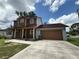 Charming two-story home with a covered front porch and attached two-car garage with a brown door at 402 E Maple St, Winter Garden, FL 34787