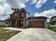 Charming two-story home with a covered front porch and attached two-car garage with a brown door at 402 E Maple St, Winter Garden, FL 34787