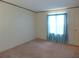 This bedroom features light-colored walls, carpeted floor, and a window with blue curtains at 432 Santa Fe E Rd, Tavares, FL 32778