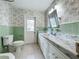 Bathroom features a tiled floor, a white marble counter and vanity, and floral wallpaper at 504 Banning Beach Rd, Tavares, FL 32778