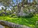 Beautiful home featuring lush landscaping, mature trees, and a well-maintained lawn along a stone-edged canal at 504 Banning Beach Rd, Tavares, FL 32778