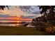 Sunset view of a wooden dock on a lake with a grassy lawn at 504 Banning Beach Rd, Tavares, FL 32778