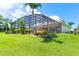 Expansive backyard featuring lush landscaping, a screened-in lanai and beautiful tropical greenery at 5418 Sandy Hill Ln, Lady Lake, FL 32159