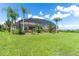 Expansive green lawn with lush landscaping leading to a screened in back porch at 5418 Sandy Hill Ln, Lady Lake, FL 32159