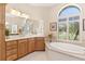 Bathroom features dual sinks, a soaking tub with a window and plenty of natural light at 5418 Sandy Hill Ln, Lady Lake, FL 32159