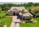 Inviting exterior of a well-manicured home featuring a brick driveway, lush lawn, and decorative palm trees at 5418 Sandy Hill Ln, Lady Lake, FL 32159