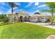 Elegant home featuring a manicured lawn, tropical landscaping, and a spacious driveway leading to a three-car garage at 5418 Sandy Hill Ln, Lady Lake, FL 32159
