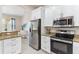 Modern kitchen featuring stainless steel appliances, granite countertops, and white cabinetry at 5418 Sandy Hill Ln, Lady Lake, FL 32159