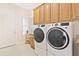 Laundry room with a set of white washer and dryer along with brown cabinets at 5418 Sandy Hill Ln, Lady Lake, FL 32159