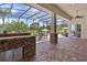 Outdoor kitchen with a stone bar, tile floors and a view of the pool at 5418 Sandy Hill Ln, Lady Lake, FL 32159