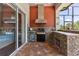Outdoor kitchen with brick floors, a grill, and sliding door into an attached room at 5418 Sandy Hill Ln, Lady Lake, FL 32159