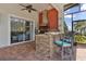 Outdoor kitchen with brick floors, a stone bar with barstools, and a view of the pool at 5418 Sandy Hill Ln, Lady Lake, FL 32159
