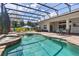 Spacious screened-in pool area with hot tub, dining, lounge area, and beautiful landscaping at 5418 Sandy Hill Ln, Lady Lake, FL 32159