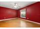 Red bedroom with wood floors, ceiling fan, and natural light, creating a comfortable living space at 5729 Bible Camp Rd, Groveland, FL 34736