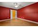 Red bedroom with wood floors, ceiling fan, and neutral paint, creating a comfortable living space at 5729 Bible Camp Rd, Groveland, FL 34736