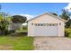 Detached garage with a large roll-up door, accented by exterior lighting and a gravel driveway at 5729 Bible Camp Rd, Groveland, FL 34736