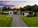 Striking modern home with lush landscaping, a paved driveway, and a welcoming entrance at sunset at 6031 Dora Dr, Mount Dora, FL 32757