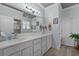 Bright bathroom featuring double sinks with light gray cabinets and light wood flooring at 6136 Lake Emma Rd, Groveland, FL 34736
