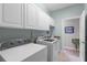 Bright laundry room featuring a washer, dryer, and overhead cabinets at 6136 Lake Emma Rd, Groveland, FL 34736