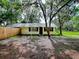 The front of the charming yellow single-story home, with lush mature trees draped in Spanish moss at 6731 Lake Griffin Rd, Lady Lake, FL 32159
