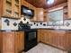Kitchen showcasing black appliances, wood cabinets, and tile flooring at 6731 Lake Griffin Rd, Lady Lake, FL 32159