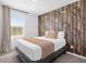 Bedroom with a rustic wood accent wall and a cozy bed next to a bright window at 709 Longboat Dr, Davenport, FL 33896