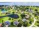 A high-angle aerial photograph shows a house with a verdant yard, many neighboring homes, and a dark pond at 7303 Spring Mountain Ln, Yalaha, FL 34797
