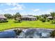 Lush backyard landscape with a serene pond view, palm trees, and a screened-in pool area at 7303 Spring Mountain Ln, Yalaha, FL 34797