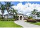 Elegant home with a circular driveway, manicured landscaping, and palm trees showcasing curb appeal at 7303 Spring Mountain Ln, Yalaha, FL 34797