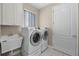 Functional laundry room features a sink, modern washer and dryer, storage cabinets, and a window at 7303 Spring Mountain Ln, Yalaha, FL 34797