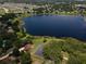 Aerial view of a community with a large lake, lush trees, and well-maintained lawns at 81 N Carol Ave, Mascotte, FL 34753