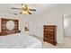 This bedroom includes wood furniture, a ceiling fan, and is adjacent to other rooms in the home at 81 N Carol Ave, Mascotte, FL 34753