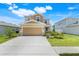Charming two-story home featuring a tan exterior, landscaped yard, and a spacious two-car garage at 853 Blue Creek Dr, Haines City, FL 33844