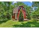 Charming red barn on a lush green property, showcasing its functional design and appeal at 9233 Silver Lake Dr, Leesburg, FL 34788