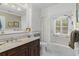 Bathroom with granite counter, vanity, white tile and beadboard, with natural light from shuttered window at 9233 Silver Lake Dr, Leesburg, FL 34788