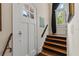 Sunlit entryway featuring hardwood stairs, a charming front door, and a decorative wall plaque at 9233 Silver Lake Dr, Leesburg, FL 34788