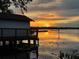 Waterfront home with dock under a bright sunset, reflecting off the water and enhancing its natural beauty at 9233 Silver Lake Dr, Leesburg, FL 34788