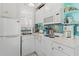 Compact kitchen featuring white appliances, glass tile backsplash, and open shelving at 9233 Silver Lake Dr, Leesburg, FL 34788