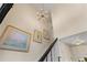 Elegant staircase with ornate chandelier and artwork on the walls, leading to a bright hallway at 9233 Silver Lake Dr, Leesburg, FL 34788