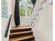 Staircase with contrasting black and white painted railings and wooden steps, leading to window-lit landing at 9233 Silver Lake Dr, Leesburg, FL 34788