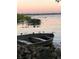 Charming waterfront scene showcasing a small boat, serene water, and lush vegetation against a backdrop of a gentle sunset at 9233 Silver Lake Dr, Leesburg, FL 34788