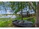 Picturesque waterfront property featuring a quaint boathouse, lush greenery, and tranquil lake views, with boat on bank at 9233 Silver Lake Dr, Leesburg, FL 34788