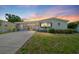 Charming single-story home with a screened-in porch and well-maintained landscaping under a beautiful sunset sky at 926 Saint Andrews Blvd, Lady Lake, FL 32159