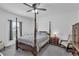 Spacious bedroom featuring a four-poster bed, a ceiling fan, a side table with lamp, and a large window at 9380 La Salle St, Groveland, FL 34736