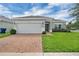 Charming single-story home with a well-manicured lawn, brick driveway, and attached two-car garage at 9380 La Salle St, Groveland, FL 34736