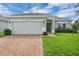 Charming single-story home featuring a brick driveway, attached two-car garage, and freshly cut green lawn at 9380 La Salle St, Groveland, FL 34736