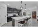 Modern kitchen features sleek, black cabinets, stainless steel appliances, and a spacious white quartz island with bar seating at 9380 La Salle St, Groveland, FL 34736