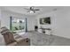 Bright living room featuring sliding glass doors, a ceiling fan, a gray sectional sofa, and a decorative area rug at 9380 La Salle St, Groveland, FL 34736