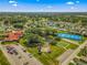 Wide aerial view showcasing community features: tennis courts, pond, shuffleboard, clubhouse, and lush landscaping at 9790 Se 175Th St, Summerfield, FL 34491